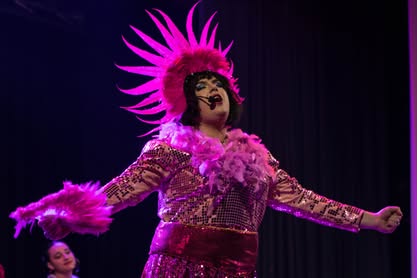 A lively scene from the Zorro pantomime featuring a performer in a bright, elaborate costume with a feathered headdress on stage. Performer dressed as Zorro in a vibrant, colourful costume during a pantomime show.