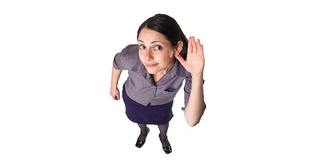 Woman with hand raised, looking up, in a professional setting.