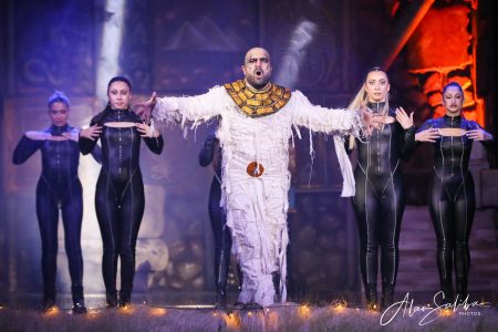 Pantomima - Il-Mummja show featuring a central performer with four dancers in a theatrical setting. A performer in a pantomime act with four dancers on stage.