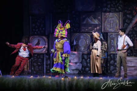 A vibrant scene from the pantomime "Il-Mummja" at Fondazzjoni Teatrali Silvio Fleri Soler, showcasing colourful costumes and expressive acting. Performers in colourful costumes enact a scene from the pantomime "Il-Mummja" on stage.