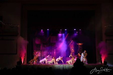 A vibrant pantomime scene with actors performing on stage, colourful lighting, and smoke effects, part of the Il-Mummja production. Theatrical performance scene with actors on stage, colourful lighting, and smoke effects during a pa.
