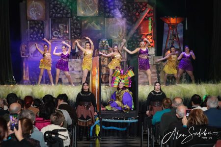 A lively scene from the pantomime "Il-Mummja" featuring dancers, a clown, and an engaged audience at Fondazzjoni Teatrali Silvio Fleri Soler. Vibrant pantomime performance with dancers and colourful costumes.
