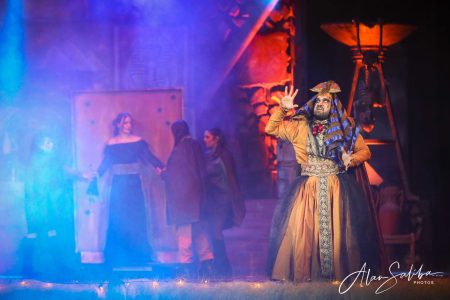 A scene from the pantomime "Il-Mummja" showcasing actors in elaborate costumes on stage. Performers in costume during a theatrical pantomime scene.