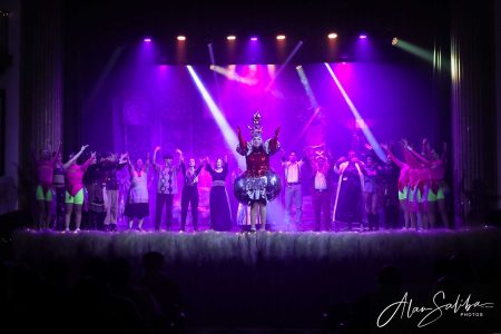 A lively scene from "Il-Mummja" pantomime, featuring performers in colourful costumes under vibrant stage lighting. Performers on stage during a theatrical pantomime show.