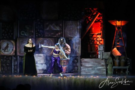 A lively pantomime scene with actors in vibrant costumes performing on stage. Performers in colourful costumes act in a theatrical scene.