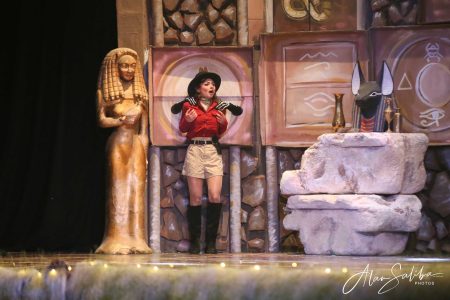 A performer in a pantomime scene portraying an ancient Egyptian character with props and set design. Performing artist in a theatrical pantomime scene with ancient Egyptian props and decorations.