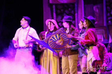 A lively scene from the pantomime "Il-Mummja" featuring actors in vibrant costumes and expressive gestures. Actors performing in a colourful pantomime scene on stage.