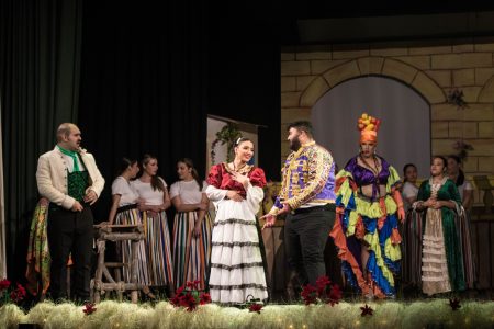 A scene from the pantomime "Zorro" featuring actors in colourful costumes on stage. An actor dressed as Zorro performing in a theatrical pantomime scene.