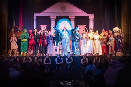A lively scene from a theatrical show featuring diverse characters and elaborate costumes on stage. Performers in vibrant costumes celebrate a theatrical production at Fondazzjoni Teatrali Silvio Fler.