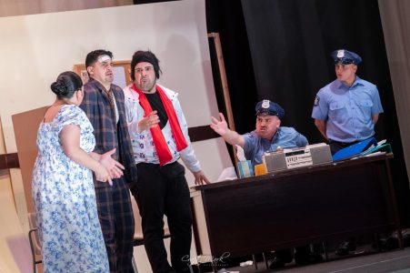 A theatrical scene featuring actors and police officers during a live performance. Actors performing a dramatic scene with police officers on stage.