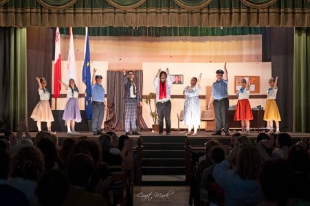 A group of actors performing a play on stage with an audience watching. Performers on stage during a theatrical show.