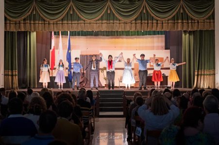 Performers take a bow after a theatrical performance at Fondazzjoni Teatrali Silvio Fleri Soler, with an audience watching attentively. Group of performers on stage during a theatrical event at Fondazzjoni Teatrali.