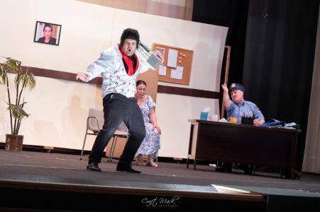 A lively scene from a theatrical production featuring actors in expressive poses, set in a professional theatre environment. Performers acting on stage during a theatrical play at Fondazzjoni Teatrali Silvio Fleri Soler.
