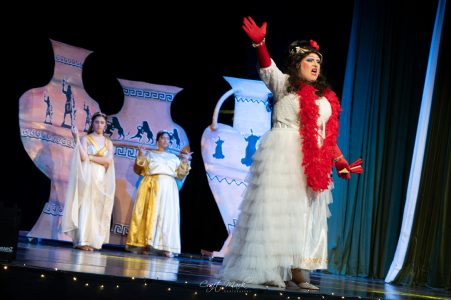 A scene from a theatrical play featuring actors in Greek costumes during a live performance. Theatrical performance with actors in Greek-inspired costumes on stage.