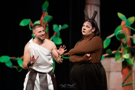 Actors engaging in a theatrical scene during a live performance at the theatre. Performers in costume on stage with colourful set design.