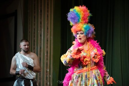 A vibrant theatrical performance with actors in elaborate costumes and dramatic expressions. An actress in colourful costume performing on stage.
