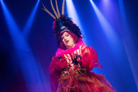 A performer in vibrant costume with elaborate headpiece during a theatrical performance at Fondazzjoni Teatrali Silvio Fleri Soler. Performer in colourful theatrical costume on stage with dramatic lighting.