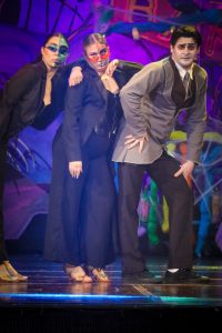 A group of actors in vibrant costumes performing in a lively theatre production. Performers in colourful costumes on stage during a pantomime show.