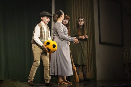 Young actors in costume engaging in a scene from the pantomime "Korps Brajd". Children performing in a theatrical pantomime on stage.