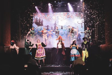 A vibrant stage scene from the pantomime "Korps Brajd" featuring performers in colourful traditional costumes. Pantomima - Korps Brajd performance on stage with dancers in traditional costumes.